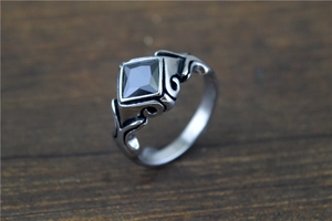 Macro detail of a vintage silver ring with a black square gemstone on a dark wood background