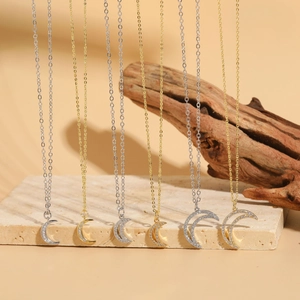 Detailed view of silver and gold crescent moon pendants with sparkling zircon stones