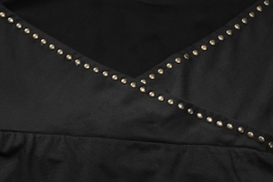 Detaillierte Nahaufnahme von Bronzenieten an einem schwarzen Kleid mit V-Ausschnitt