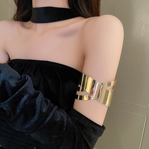 Dettaglio di un bracciale rigido dorato geometrico a strati sul braccio di una modella