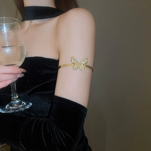 Detailed view of luxury gold butterfly arm cuff with sparkling crystals on velvet dress