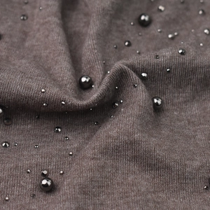 Macro detail of dark brown knit beanie with stylish metallic grey beads and soft texture