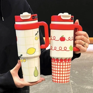 Détail de mugs isothermes avec motifs de fruits et poignées rouges ergonomiques