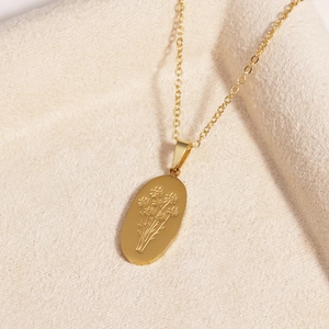 Macro shot of an irregular oval gold pendant featuring an engraved floral rose pattern