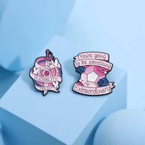 Pink enamel sword and gem pins with inspirational text on a blue background