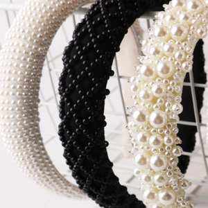 Three-piece pearl headband set with vintage beaded designs on a white metal rack