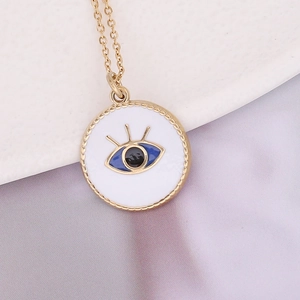 Bohemian gold stainless steel necklace with blue evil eye pendant on soft fabric