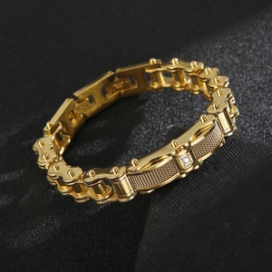 Dettaglio di un bracciale a catena da moto dorato con texture a rete e diamante incastonato
