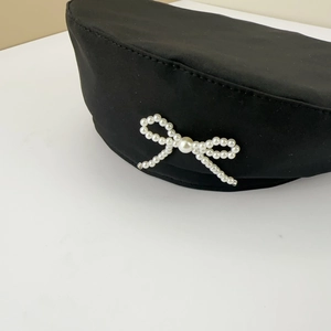 Elegant black beret hat for women featuring a stylish faux pearl bow accent on white background