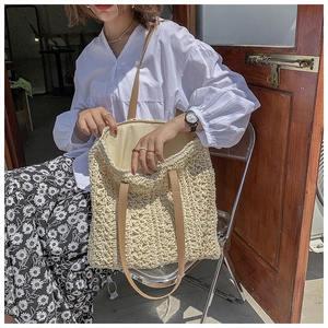 Close-up of beige woven tote bag with brown straps and spacious yellow fabric interior