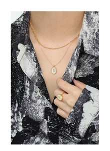 Close-up of vintage gold layered necklace and ring with tulip flower shell inlay