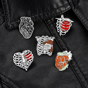 Set of five anatomical heart and ribcage enamel pins on a black leather jacket background