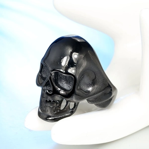 Detail shot of a black punk skull ring with intricate bone carvings on a display stand