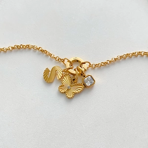 Close-up of gold-plated stainless steel necklace with butterfly and S-letter charms