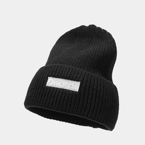 Close-up of black ribbed knit beanie featuring an embroidered white THE FOCUS logo patch