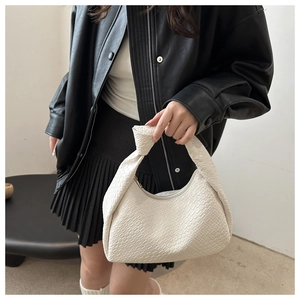 Close-up of white woven PU leather handbag featuring a unique knotted handle design