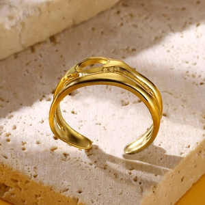 Detailed close-up of golden irregular textured ring placed on a natural beige stone