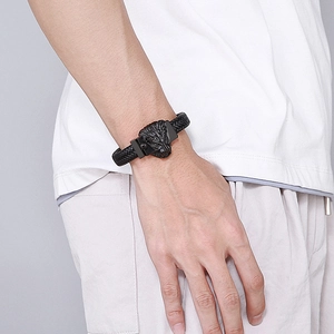 Détail d'une breloque tête de lion en acier inoxydable sur un bracelet en cuir tressé noir