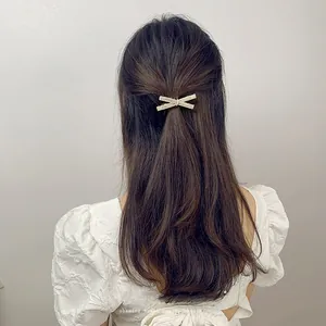 Detailed view of elegant bow hair clip with cream pearls on wavy brown hair