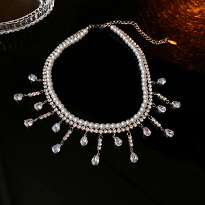 Détail d'un collier double rang avec perles blanches, zircons et glands en cascade
