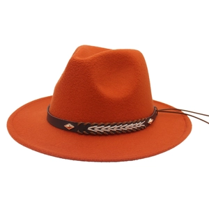 Detail of orange wool fedora featuring a brown band with beige weave and metal studs