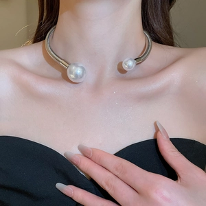 Close-up of a silver metal choker with large faux pearls on a fashion model's neck
