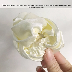 Detail of creamy white satin scrunchie showing the layered petal folds and silky texture