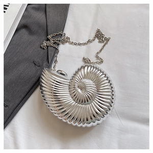 Macro detail of silver snail shell shaped evening clutch with glossy metallic spiral texture