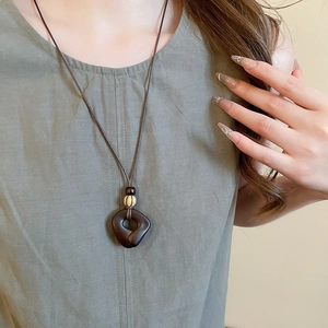 Detail of vintage irregular resin wood pendant on ethnic tassel necklace worn by model