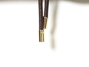 Détail d'un cordon en cuir tressé marron avec embouts en métal doré de qualité