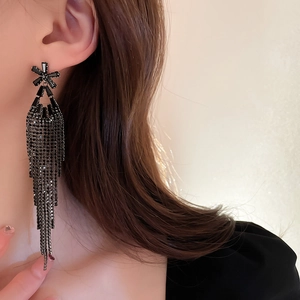 Macro shot of elegant black rhinestone flower long tassel earrings worn by a model