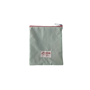 Light green macaron makeup bag with zipper closure and white label on white background