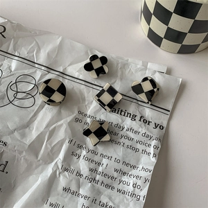 Checkered black and white hair clips in assorted shapes on a vintage newspaper background