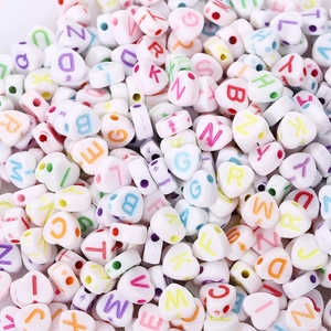 Macro shot of white acrylic heart beads with colorful alphabet letters for DIY jewelry
