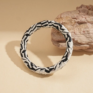 Detail of zebra pattern wrap cuff bracelet featuring woven black and white leather texture