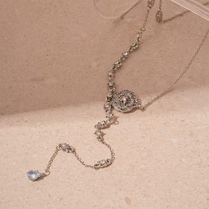 Close-up of silver floral sweater necklace with sparkling rhinestones and blue teardrop gem