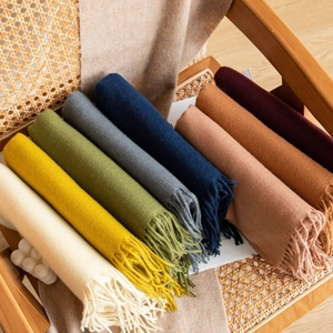 Dettaglio di varie sciarpe colorate con nappe su una sedia di legno rustica