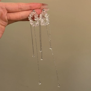 Macro detail of long silver fringe earrings with clear irregular crystal ring pendant