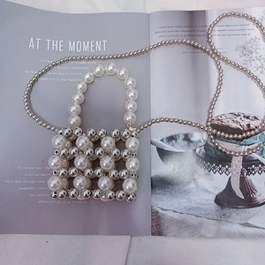 Close-up of handmade mini beaded bag with white faux pearls and silver metal beads