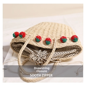 Detail of straw tote with knitted strawberry charms and polka dot drawstring lining