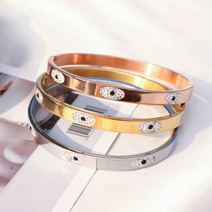 Close-up of three evil eye stainless steel bangles in gold, rose gold and silver finishes