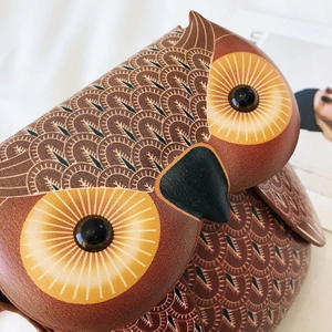 Macro view of owl-shaped shoulder bag showing detailed feather texture and embroidery