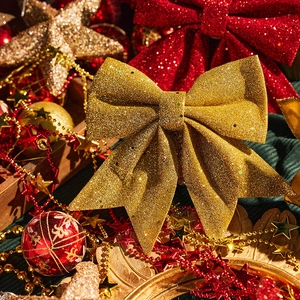 Sparkling gold Christmas bow with festive red ornaments for tree and wreath decoration