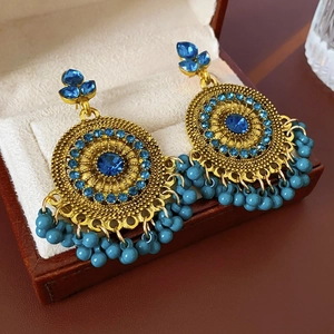 Detailed macro view of vintage gold disc earrings with blue crystals and beaded tassels