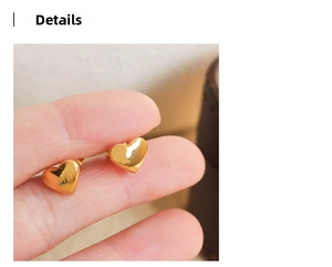 Detailed close-up of a polished gold heart-shaped earring held by fingers