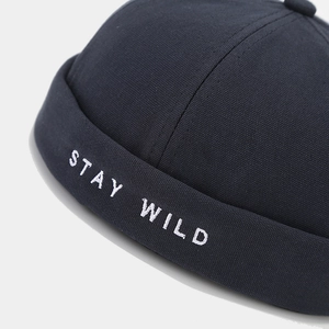Navy canvas docker hat featuring white 'STAY WILD' letter embroidery and stitching