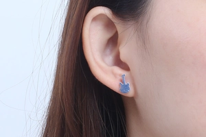 Close-up of silver guitar-shaped stainless steel stud earring worn by a model