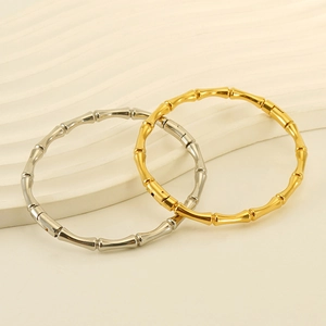 Close-up of gold and silver bamboo-style stainless steel bangles on textured stand