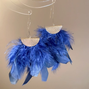 Detailed macro view of deep blue feather tassel earrings with textured gold finish