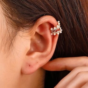 Close-up of a silver ear cuff with pearls and diamonds worn on a model's ear